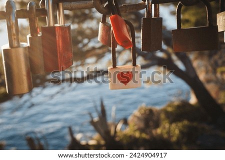 Lock with red heart on the bridge over the sea