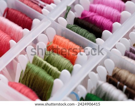 A close-up shot of a plastic sorting box full of bobbins with different colour embroidery threads. Royalty-Free Stock Photo #2424906415