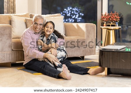Loving grandfather tickling granddaughter and having fun at home