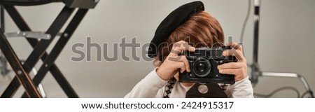 boy in beret captures the moment on retro camera, horizontal banner of young photographer