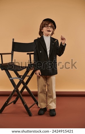 inspired boy standing near director chair, with a smile on face showing idea sign,  profession