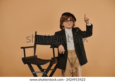happy boy standing near director chair, with a smile on face showing idea sign,  profession