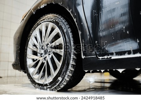 object photo of shining tired of black modern auto covered with soap during car detailing service