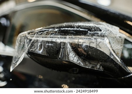 object photo of transparent protective foil applied on side view mirror of black modern car