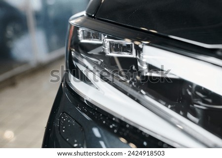 object photo of black modern automobile with its headlights in garage during cleaning service