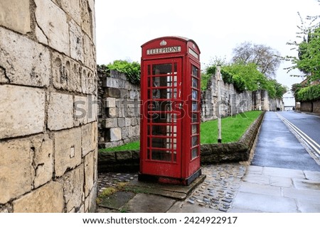 A Classic Red Telephone Booth Amidst Historical Stone Walls