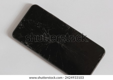 a photo of a cellphone whose screen has been cracked or broken on a white background 