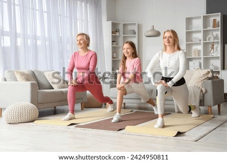Sporty little girl with her mom and grandmother training at home Royalty-Free Stock Photo #2424950811