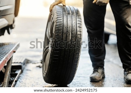Cropped picture of vulcanizing worker with car tire.