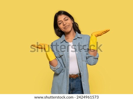woman in protective gloves listening to music by wireless headphones, singing, using brush as microphone on yellow background. enjoying making domestic chores