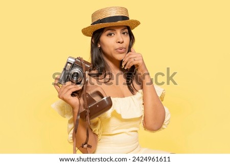 a woman inyellow dress and hat taking photos by vintage camera on a yellow background. Happy people going on holiday, vacation