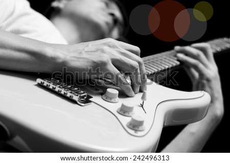 male musician playing electric guitar, isolated on black. bw filter & colorful bokeh