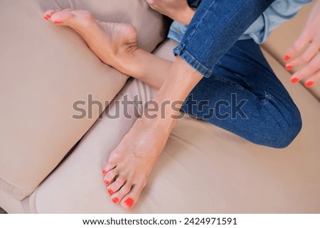 beautiful female feet with long toes and orange nail polish close-up on the sofa Royalty-Free Stock Photo #2424971591