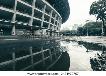 Gelora Bung Karno (GBK) Stadium after rain, water reflecting on the running track, with several people jogging in cloudy weather. A sports complex in the capital city of Jakarta, Indonesia.  Royalty-Free Stock Photo #2424972757