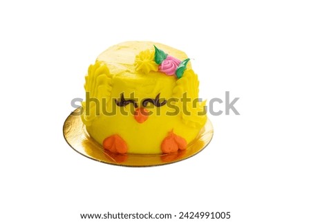 Isolated baby chick mini cake for easter. Yellow body with orange feet and beak. Topped with a pink rose and green leaves. Sits on gold doily.