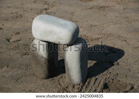 Three square shaped rocks stacked to make a mini Stonehenge on the beach.