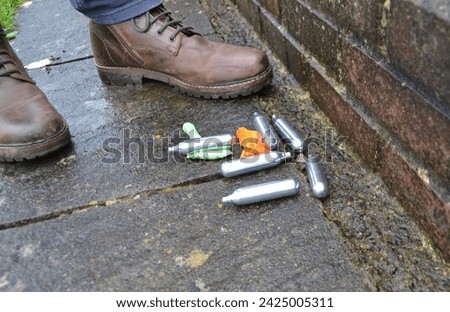 Nitrous oxide gas canisters with balloons, drug misuse Royalty-Free Stock Photo #2425005311