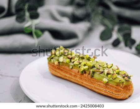Sweet eclairs with dry pistachios on plate Royalty-Free Stock Photo #2425008403