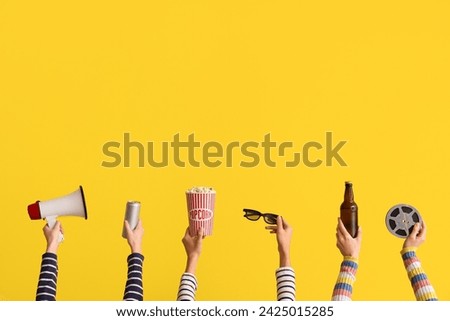 Many hands with bucket of popcorn, drinks and megaphone on yellow background