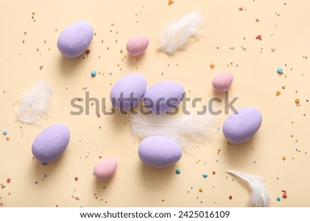 Painted Easter eggs with feathers on beige background