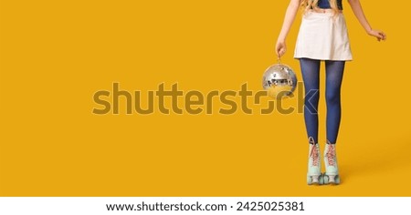 Young woman in vintage roller skates and with disco ball on yellow background with space for text