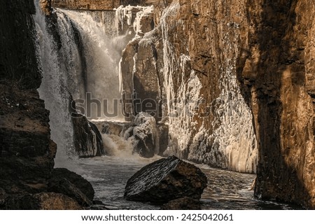 Landscape photo of Paterson Great Falls in New Jersey in a cold winter showing ice build up with soft evening light lighting up the gorge