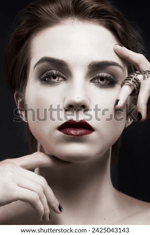 Beauty, woman and gothic makeup in studio with portrait for cosmetics, art deco aesthetic with edgy jewelry. Face of model in villain character, vampire and red lipstick on a dark or black background