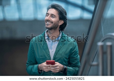 View of young man using a smartphone at twilight in an indoor space with a blurred view landscape in the background. High quality photo. 