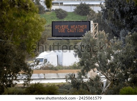 Digital road sign stating Severe Weather Use Caution with a truck passing under it. The shot is on the 15 freeway in Escondido California