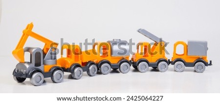 Construction vehicles lined up in a row. Multi-colored children's toys plastic trucks on a white background.