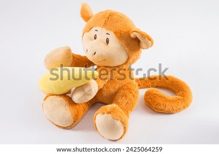 Plush children's toy monkey with banana on a white background.
