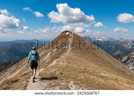 Hiker woman on idyllic hiking trail on alpine meadow with scenic view of majestic Hochschwab mountain range, Styria, Austria. Wanderlust in remote Austrian Alps. Sense of escapism, peace, reflection Royalty-Free Stock Photo #2425068767