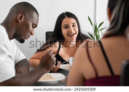 latina girl very happy and laughing out loud while eating with her friends seated in the dining room