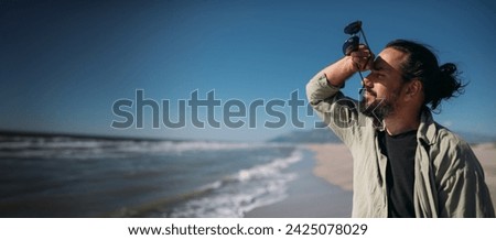 A young man is relaxing on a sandy sea beach. A relaxed, happy Caucasian guy looks at the sea and the sunlight on the ocean on a sunny day Royalty-Free Stock Photo #2425078029