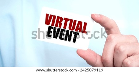 Man in blue sweatshirt holding a card with text VIRTUAL EVENT, business concept