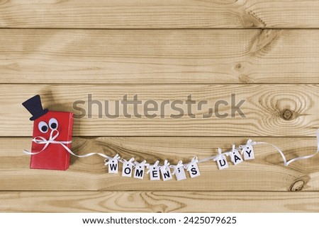 Women's Day. Gentleman man funny congratulations on the holiday. Red gift box and inscription in letters Womens Day. Royalty-Free Stock Photo #2425079625