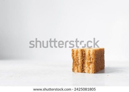A slice of vanilla cake with jam filling, thin layers of vanilla and chocolate cake with jam filling on a white background Royalty-Free Stock Photo #2425081805