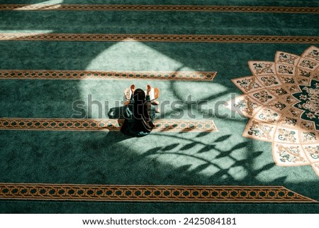 A Muslim woman praying inside the mosque with hands up. Royalty-Free Stock Photo #2425084181