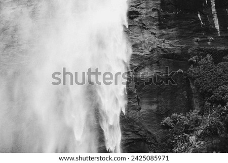 Textured black and white background of wild natural New Zealand travel landmark high Milford Sound waterfall cascade spray and rocky mountainside 