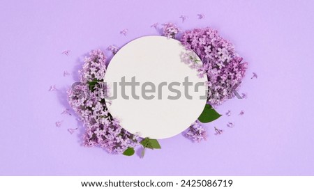 Natural branches and flowers of lilac near round white piece of paper. Сoming of spring. Lilac background. Template for text or design. Greeting card. Copy space. Flat Lay.