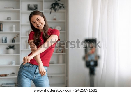 Blogging Concept. Cheerful Asian Woman Dancing At Camera, Young Korean Female Making Funny Dance While Recording Video At Home, Positive Lady Using Smartphone On Tripod, Free Space Royalty-Free Stock Photo #2425091681