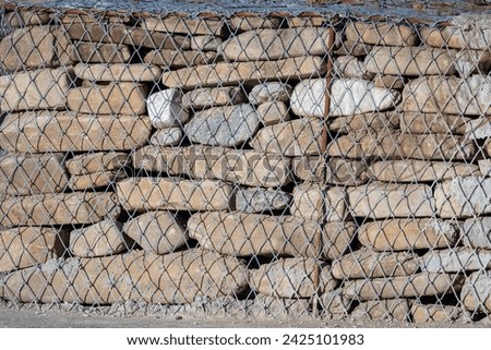 Picture of a gabion made of stone and iron. Gabions can flex to ground movement, dissipate energy from flowing water, and drain freely
