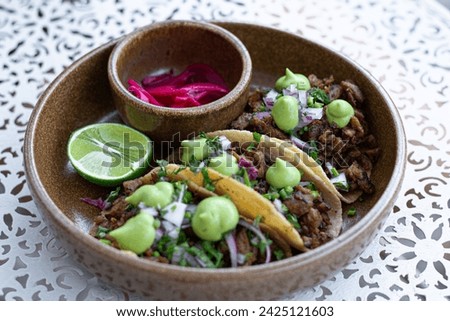 Delicious and authentic Mexican meal of carnitas tacos, with handmade tortillas, and are filled with tender, carnitas, topped with cilantro, onions, and a dollop of traditional Mexican green salsa