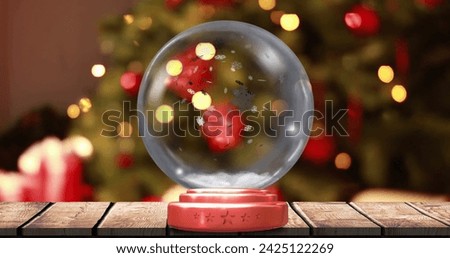 Image of christmas snow globe snow falling and christmas tree with fairy lights. Christmas, festivity, tradition and celebration concept digitally generated image.