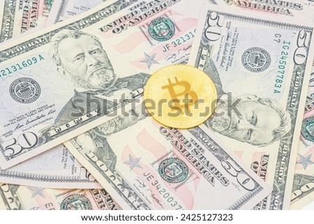 Bitcoin cash BTC, cryptocurrency pictured as a gold, gold coin lying over dollars, real US money, 50 dollars, United States fifty-dollar bill. Bitcoin on top of United States Dollar Banknotes.