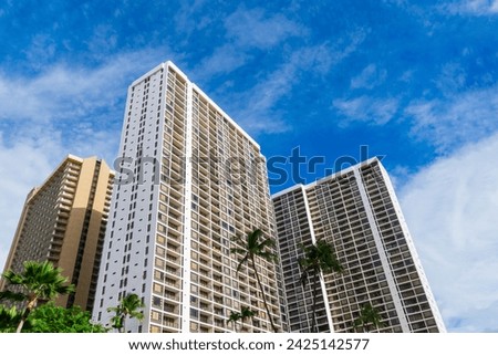 Exterior view of modern high rise residential buildings framed by lush palm trees Royalty-Free Stock Photo #2425142577