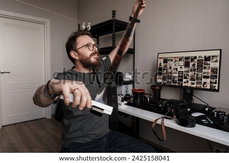 An adult man contrasts traditional film inspection with modern digital archiving, symbolizing the evolution of photography in a studio