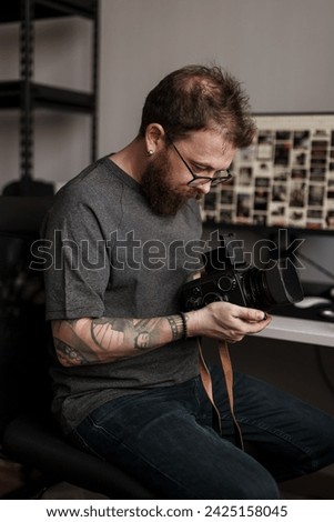 A focused man examines a medium format camera, immersed in the intricate art and technical precision of photography in a studio setting