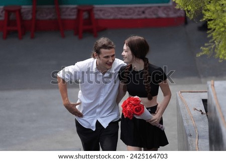 couple young man and woman hugging and holding the red bouquet rose flowers at outdoor space. Concept couple life with love and happy moment.