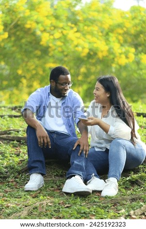 Couple, black husband and Asian wife,  happily hugging and talking in the garden Royalty-Free Stock Photo #2425192323